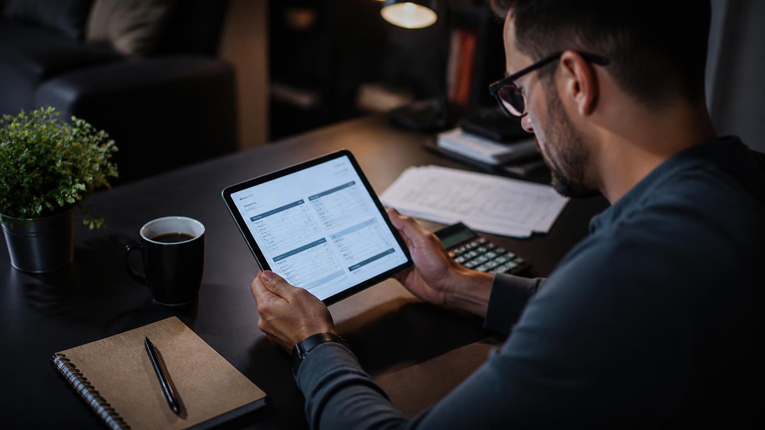 Designer revisando orçamentos em um tablet sobre uma mesa escura