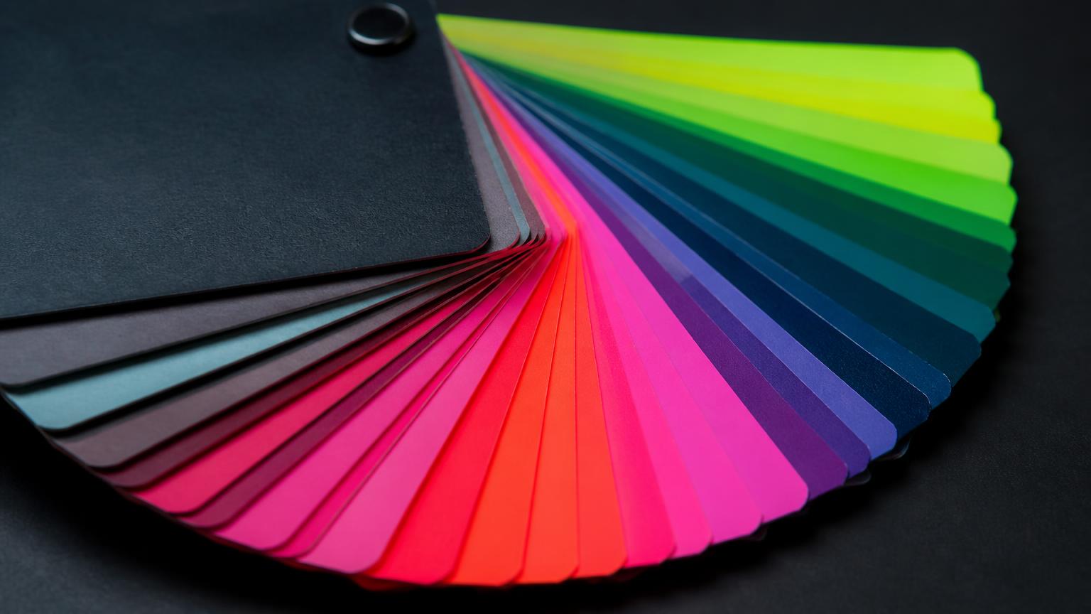 Leque de cartelas de cores vibrantes aberto sobre superfície escura